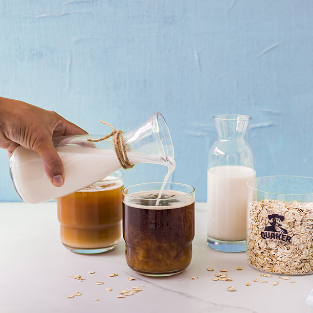 Oat milk being poured into a cup of tea